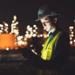 Night worker with helmet holding a tablet