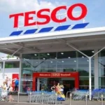 Front of a tesco store with a logo on top of it.